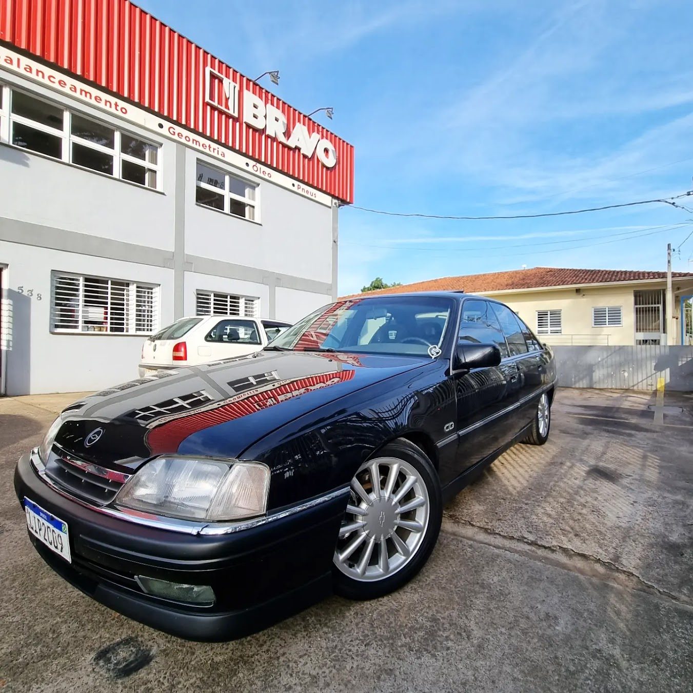 Fachada da Bravo Auto Center com Chevrolet Omega preto estacionado